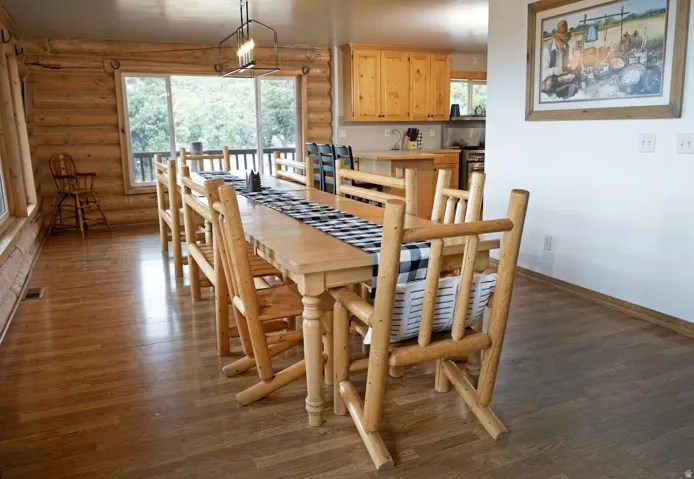 Dining space with dark wood-type flooring, log walls, and a chandelier