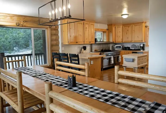 Kitchen with light countertops, plenty of natural light, decorative light fixtures, range with gas stovetop, and log walls