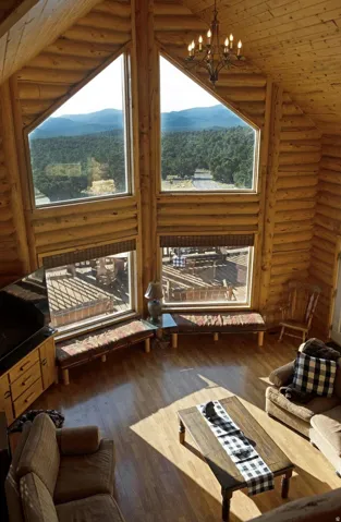 Living area with log walls, dark wood finished floors, a chandelier, wooden ceiling, and high vaulted ceiling