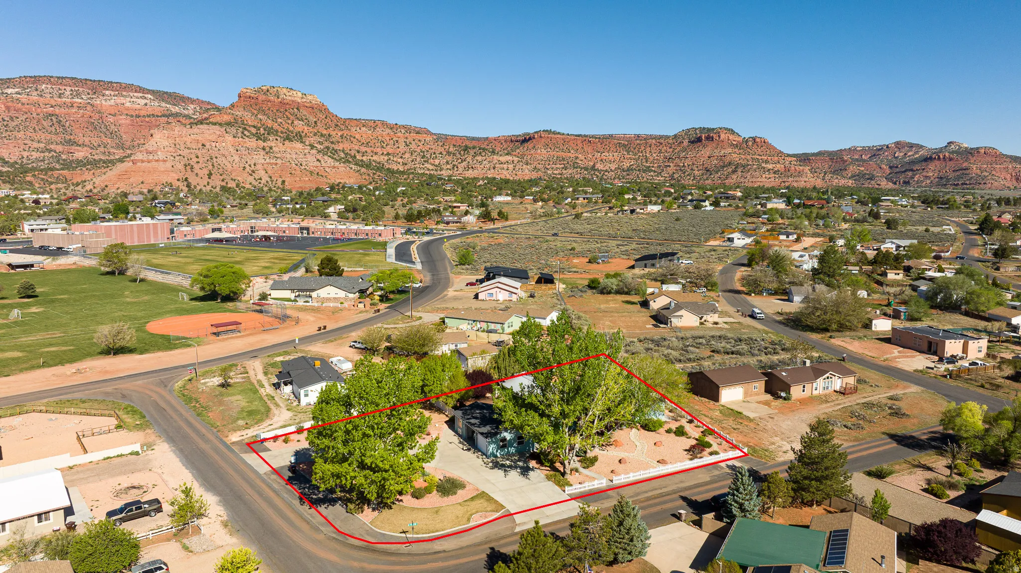 Aerial perspective of suburban area featuring property boundaries highlighted and a mountain backdrop
