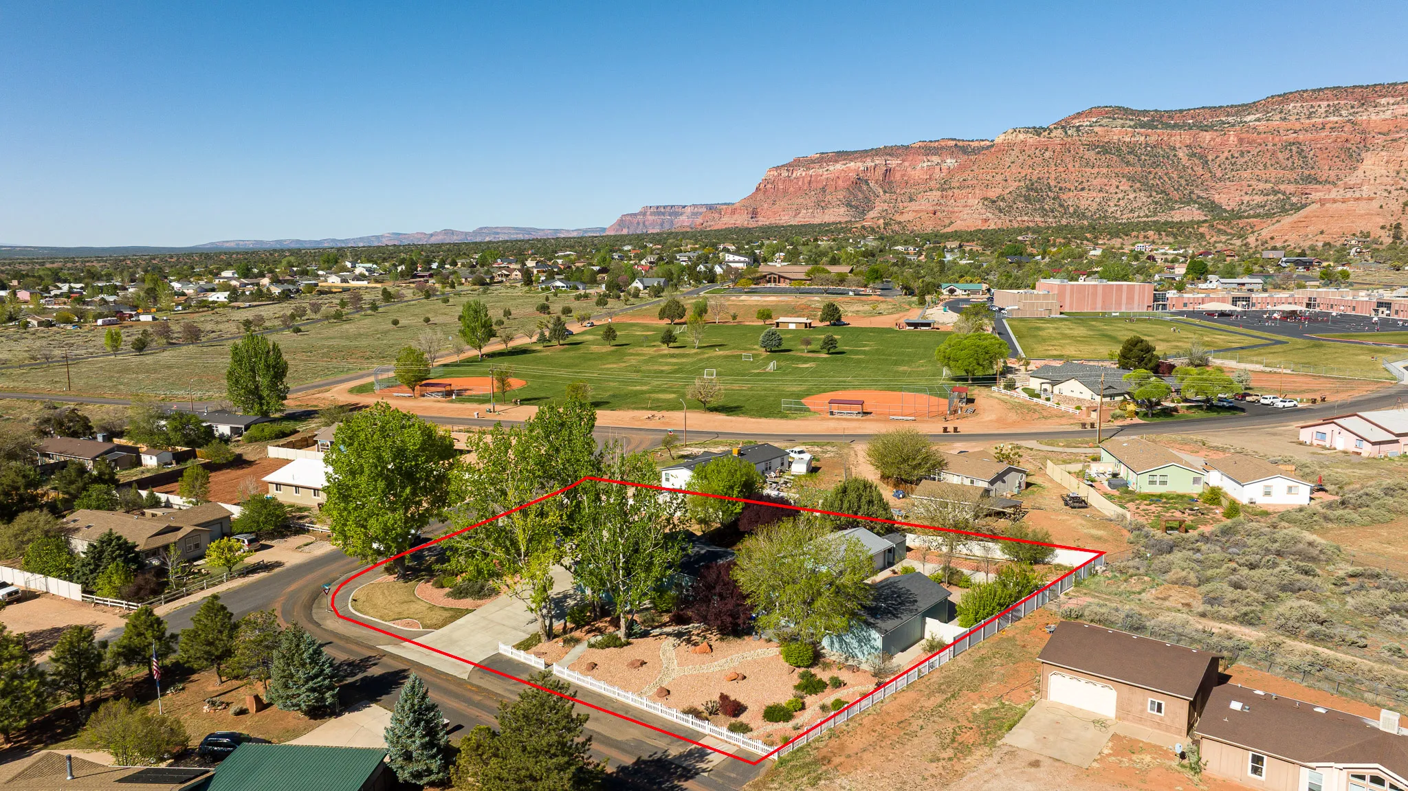 Aerial view of residential area with property parcel outlined and mountains