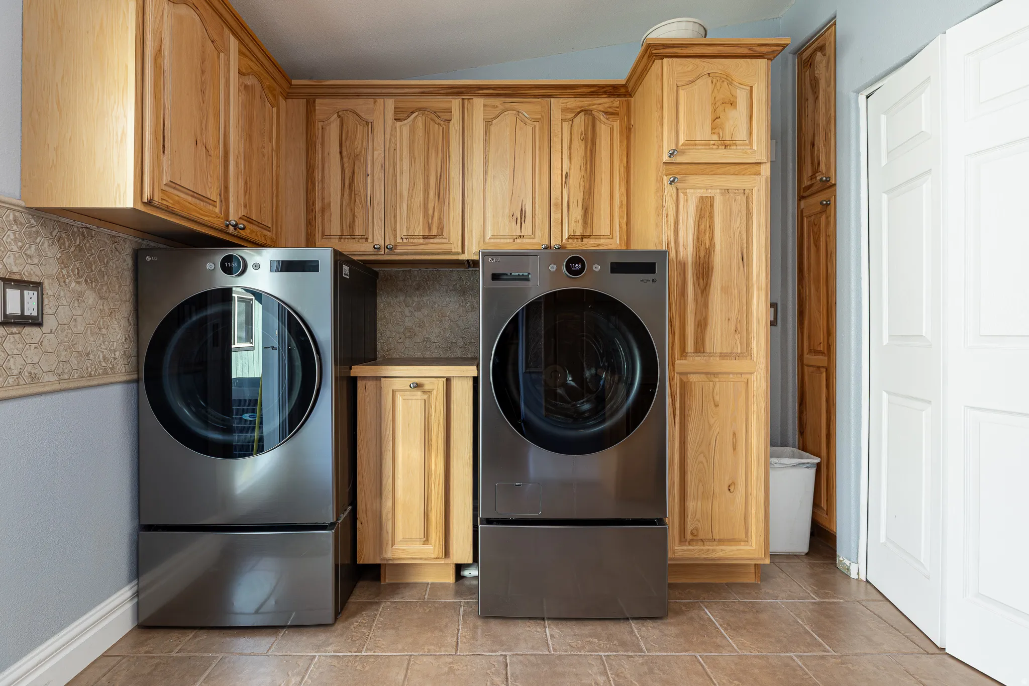 Laundry room with separate washer and dryer, cabinet space, and tile floors