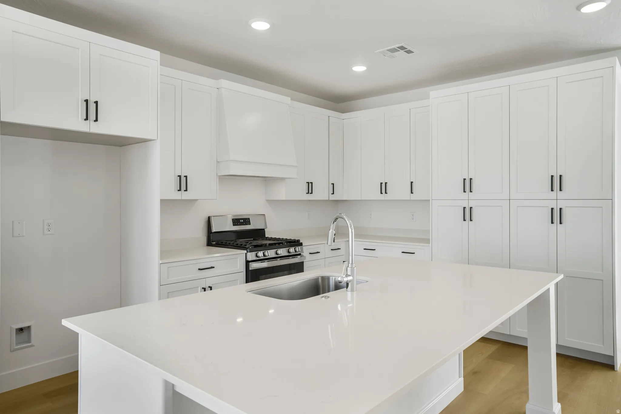 Modern kitchen featuring an expansive island with an undermount sink and gooseneck faucet