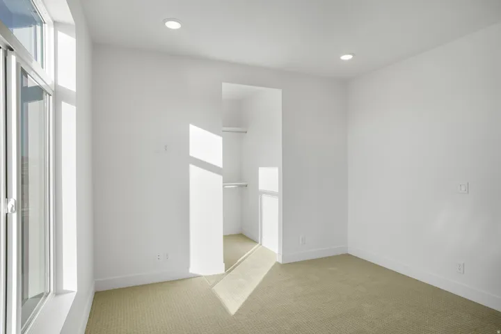 Carpeted room featuring a built-in closet with shelving and hanging rods