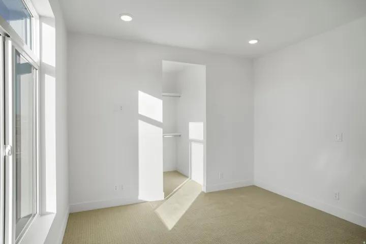 Carpeted room featuring a large window, recessed lighting, and a built-in closet with shelving and hanging rods