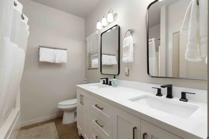 Full bath featuring double vanity, dark tile patterned floors, and shower / tub combo