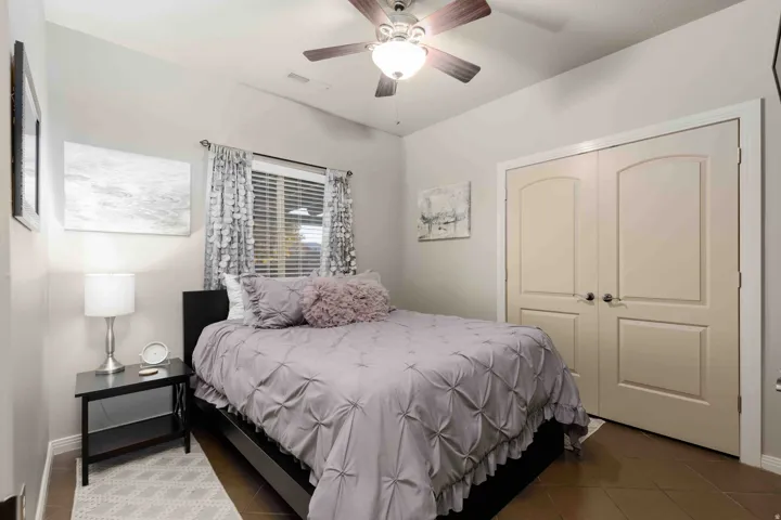 Bedroom featuring tile patterned flooring, a closet, and a ceiling fan