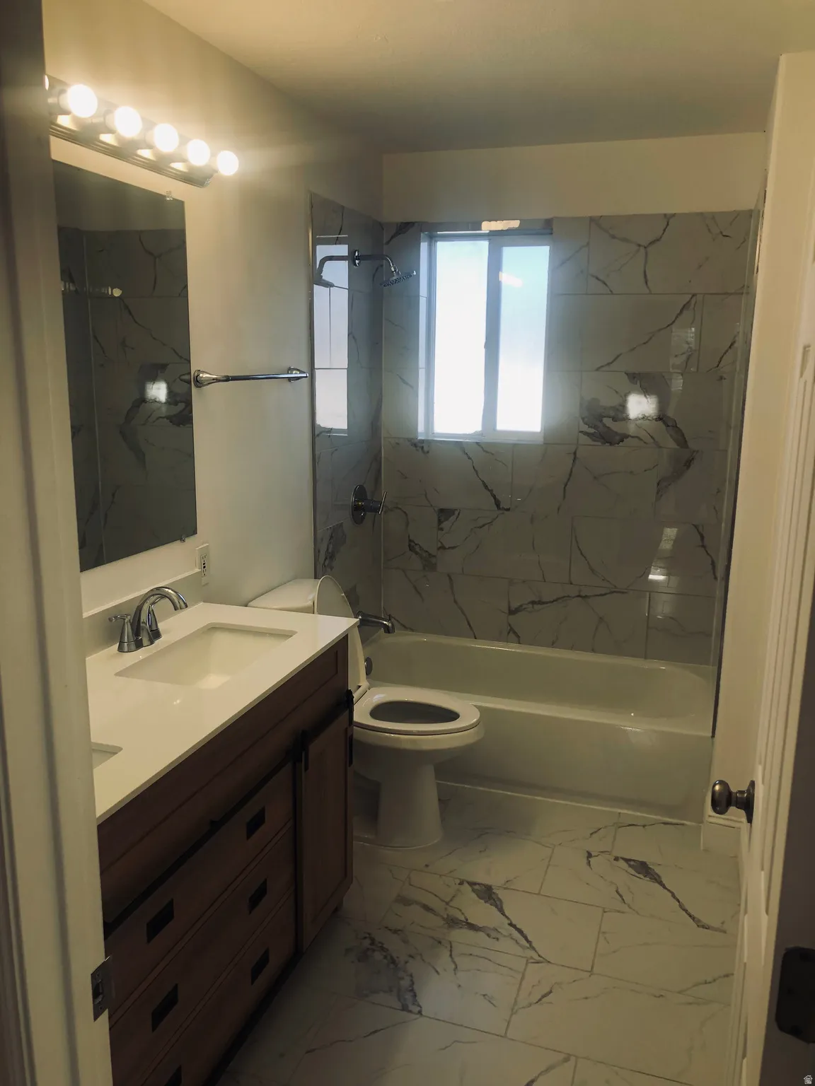 Bathroom with vanity, bathtub / shower combination, and light marble finish floors
