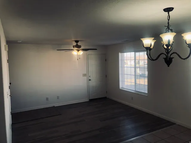 Spare room featuring a chandelier, dark wood-type flooring, and ceiling fan