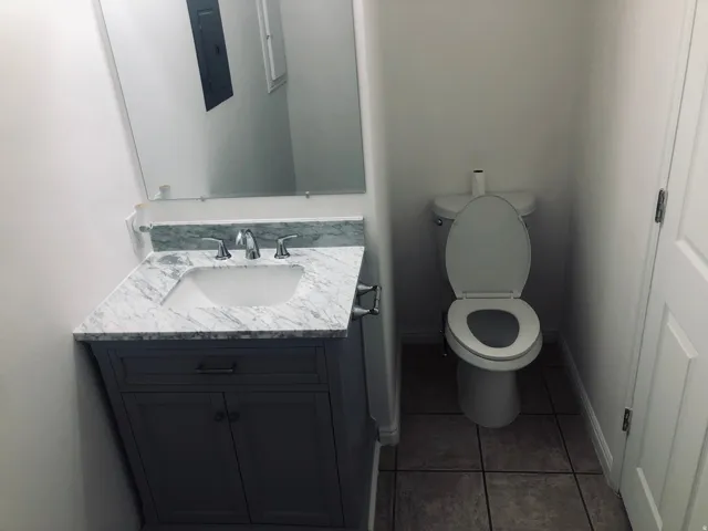 Half bathroom with vanity, dark tile patterned floors, and electric panel