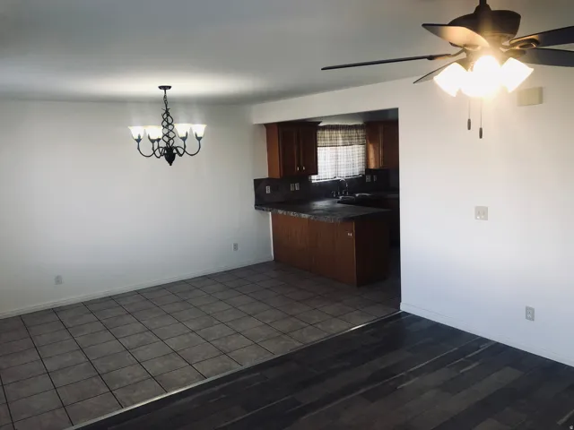 Kitchen featuring dark countertops, backsplash, a ceiling fan, a chandelier, and dark wood-type flooring
