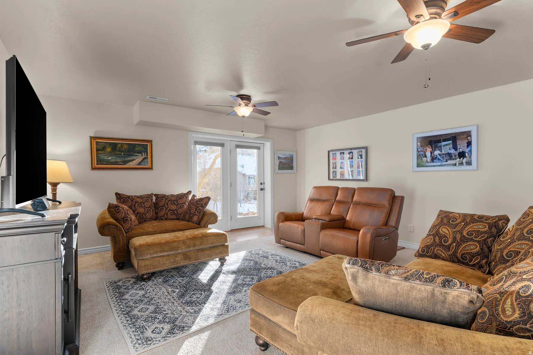 Carpeted living area with ceiling fan and baseboards