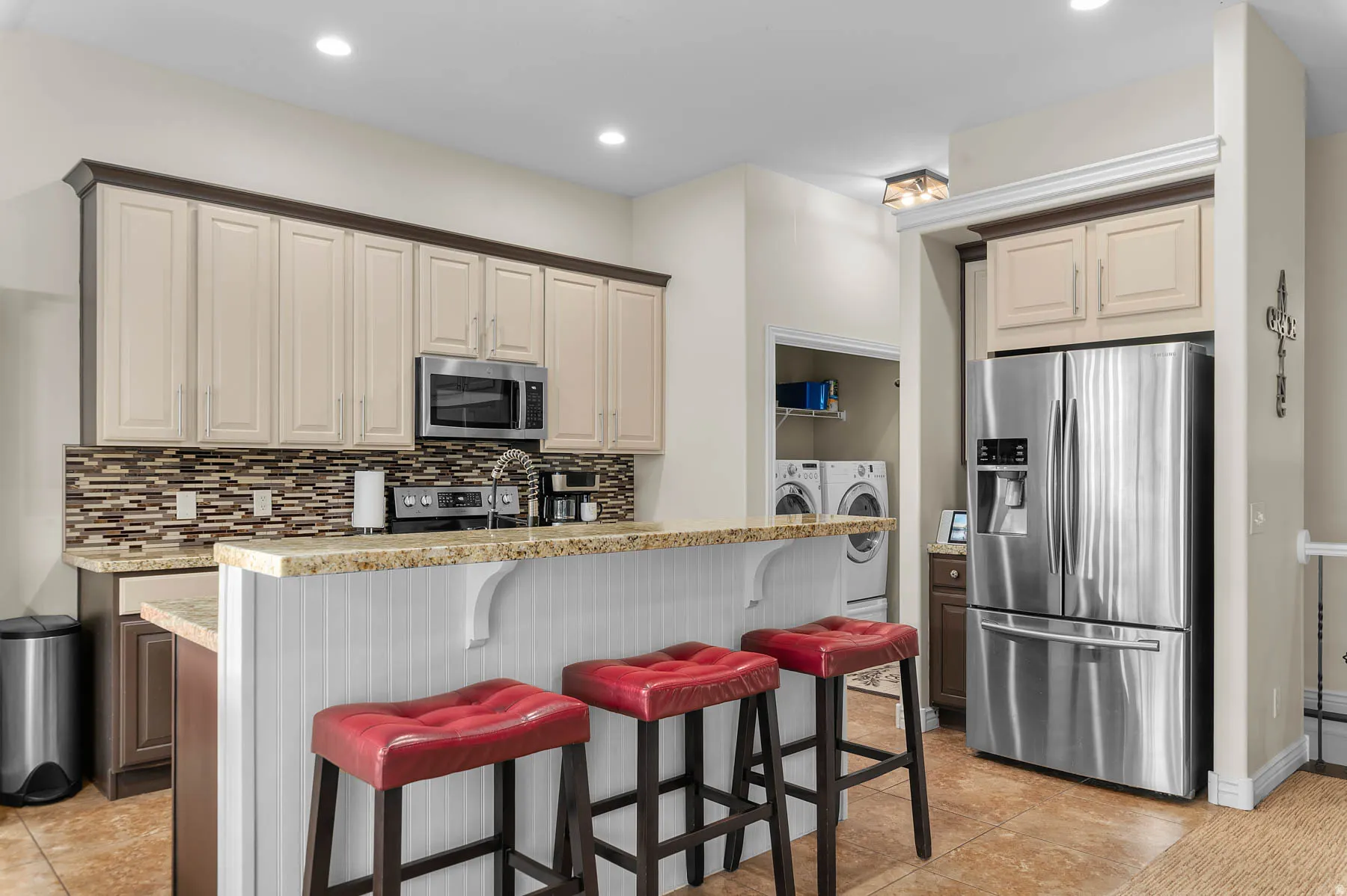 Kitchen with stainless steel appliances, decorative backsplash, a kitchen breakfast bar, light stone counters, and recessed lighting