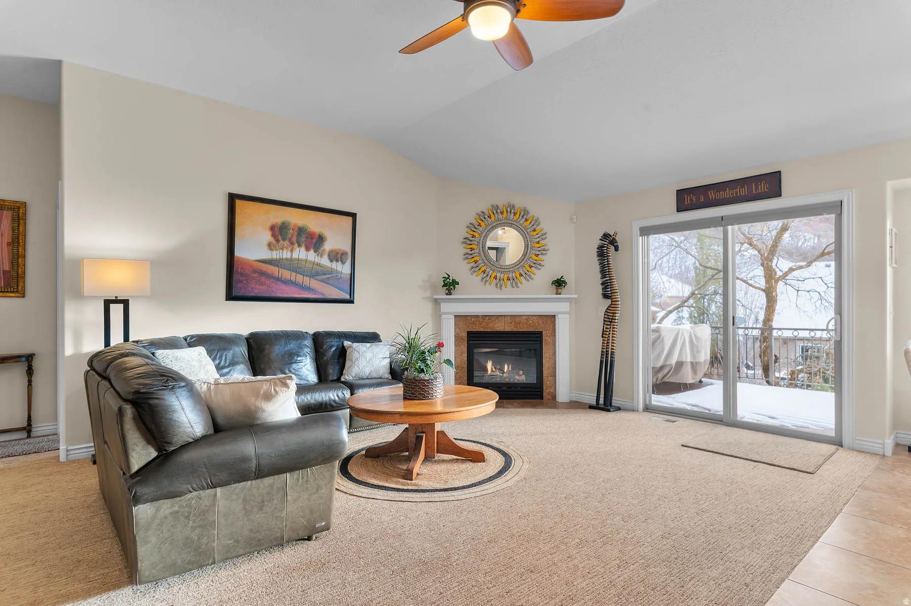 Living room with a fireplace with flush hearth, light carpet, lofted ceiling, ceiling fan, and light tile patterned flooring