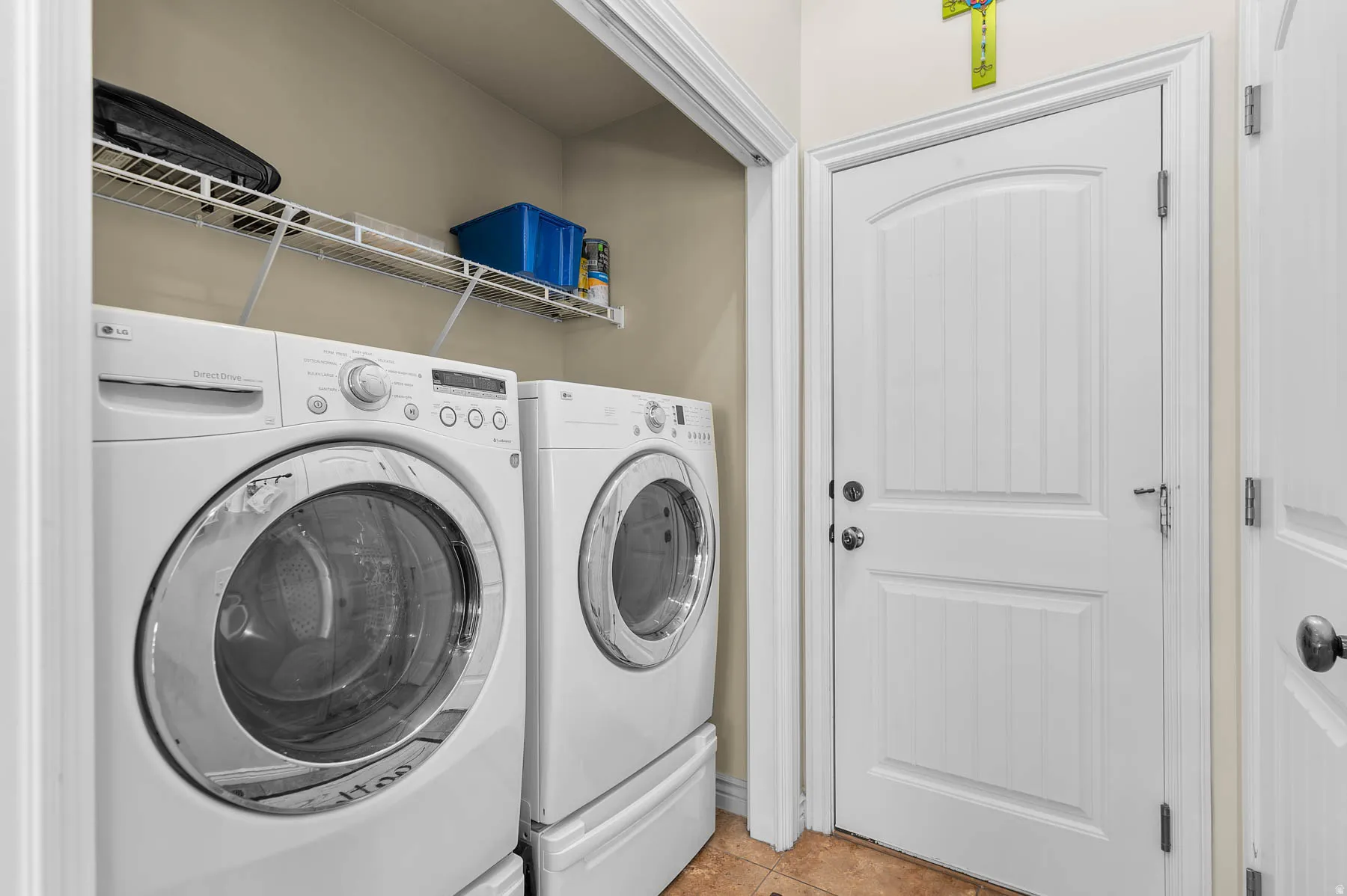 Laundry room with washing machine and clothes dryer and light tile patterned flooring