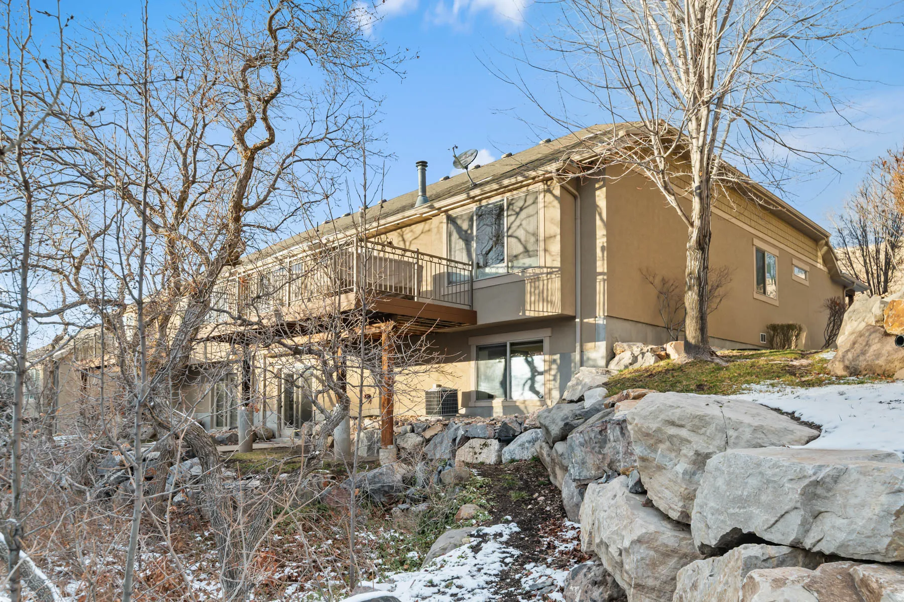 Snow covered rear of property featuring stucco siding and a wooden deck