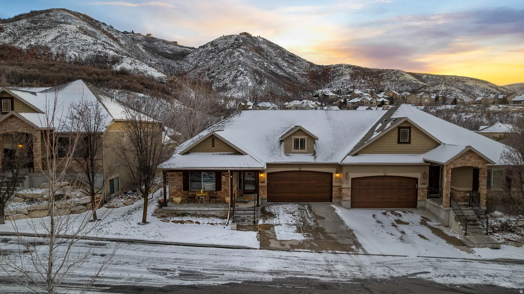 View of front facade featuring covered porch, stone siding, a mountain view, and driveway