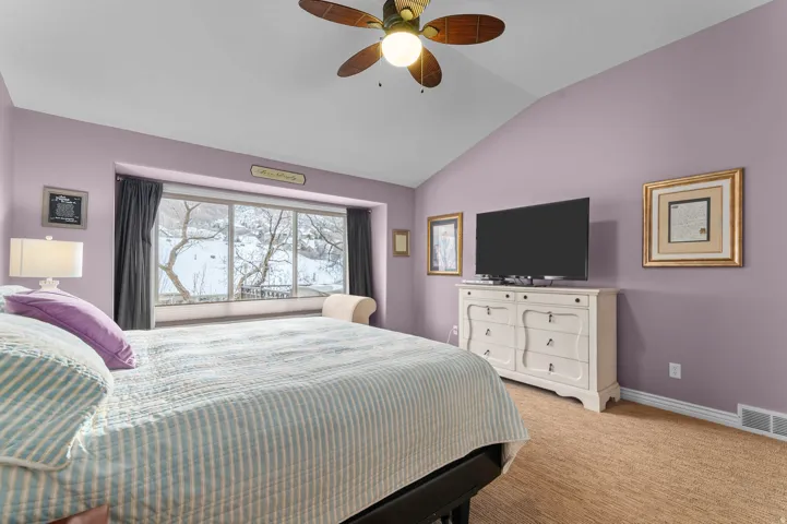 Bedroom featuring vaulted ceiling, light carpet, and ceiling fan