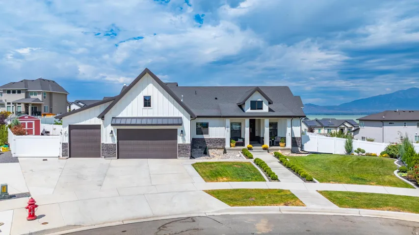 Modern farmhouse with board and batten siding, a porch, stone siding, driveway, and an attached garage