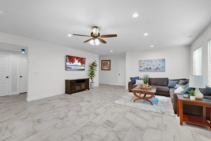 Living area with recessed lighting, a ceiling fan, and light marble finish flooring