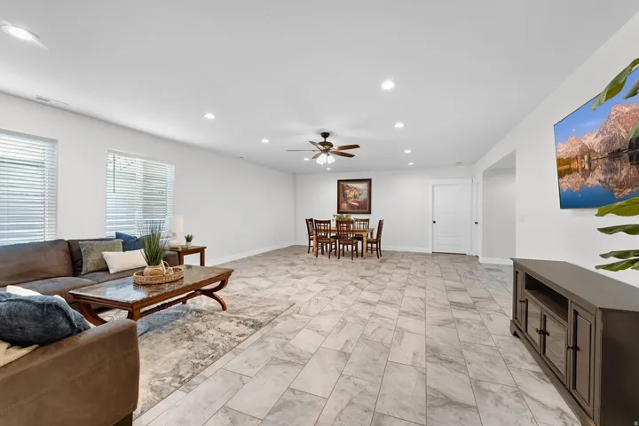 Living area with recessed lighting, ceiling fan, and light marble finish flooring