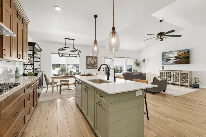 Spacious open-concept layout with wood-finish flooring, a kitchen island with sink, ample cabinetry, and recessed lighting
