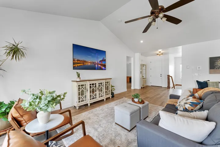 Living room featuring lofted ceiling, wood finished floors, and ceiling fan
