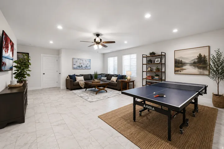 Recessed lighting throughout, light-toned tile flooring, ceiling fan, white paneled door, and multiple windows with blinds