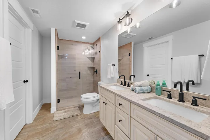 Bathroom with double vanity, a shower stall, and wood tiled floors
