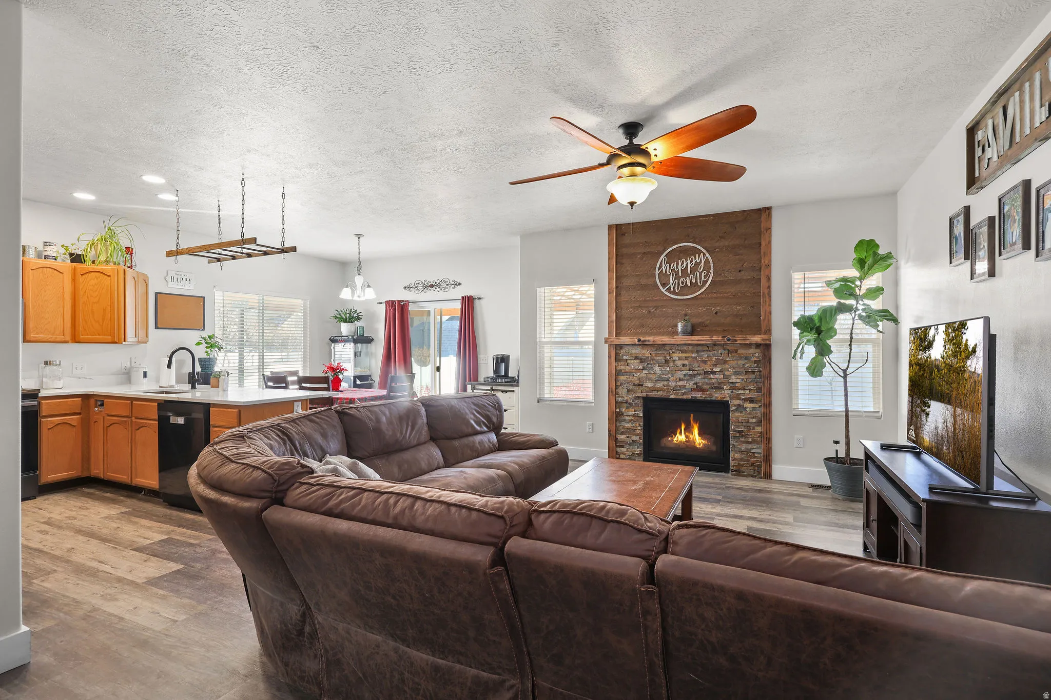 Living room featuring a ceiling fan, a textured ceiling, dark wood-style flooring, and a large fireplace