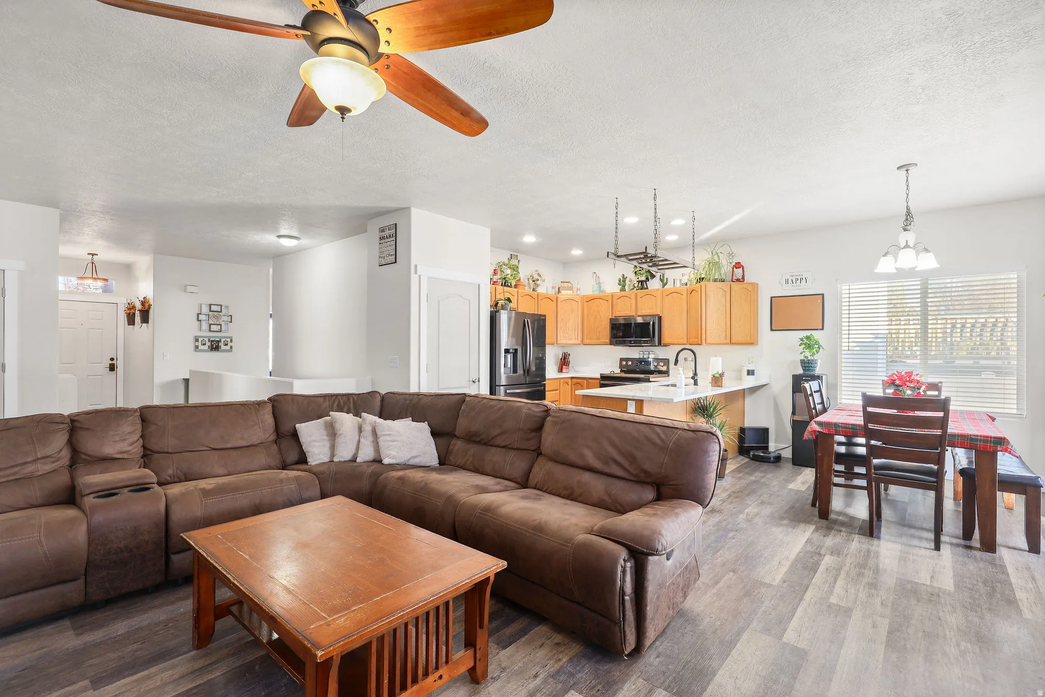 Living area with a chandelier, a textured ceiling, ceiling fan, light wood-style flooring, and recessed lighting