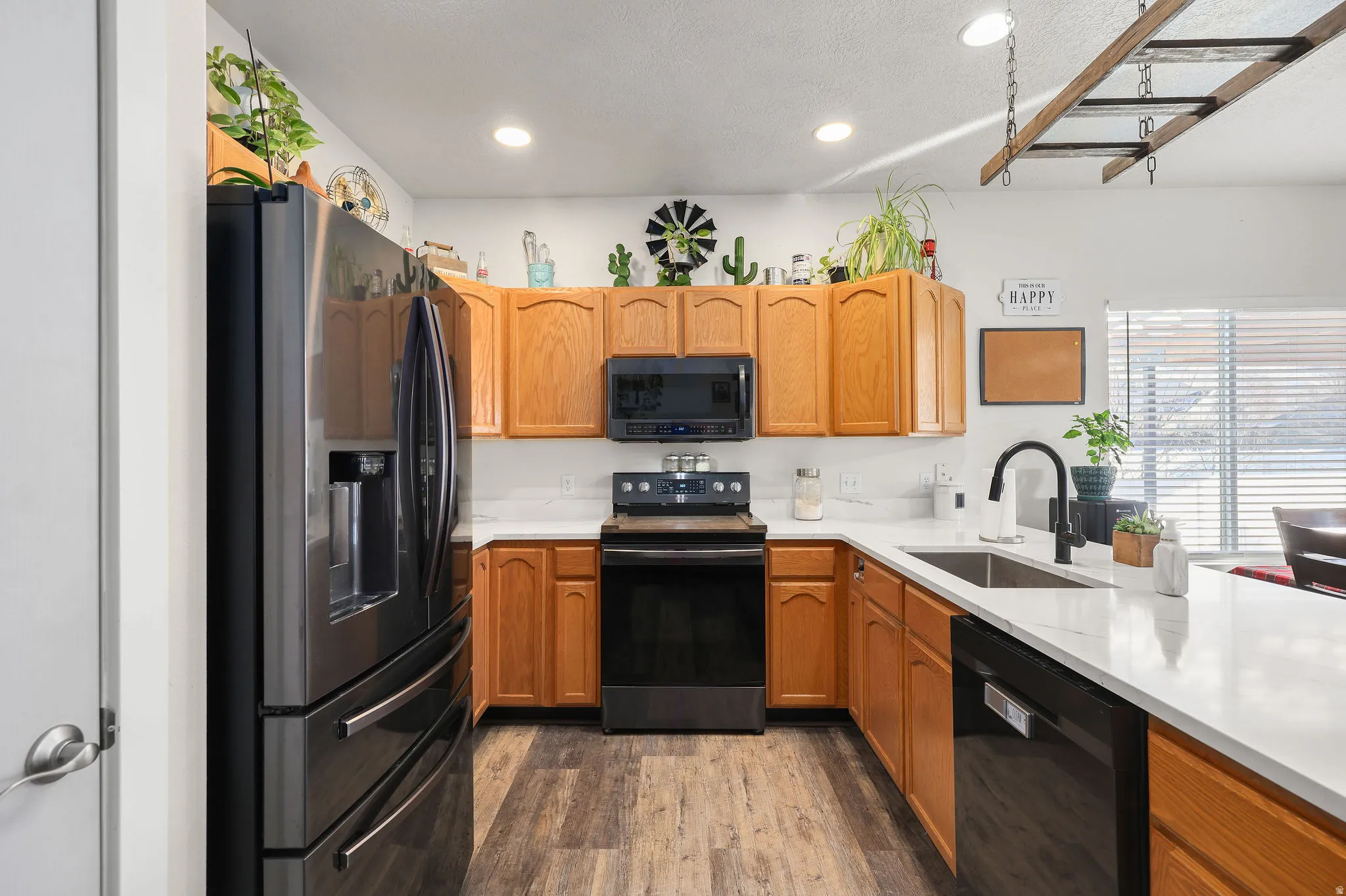 Kitchen with black appliances, recessed lighting, dark wood-type flooring, light stone countertops, and brown cabinetry
