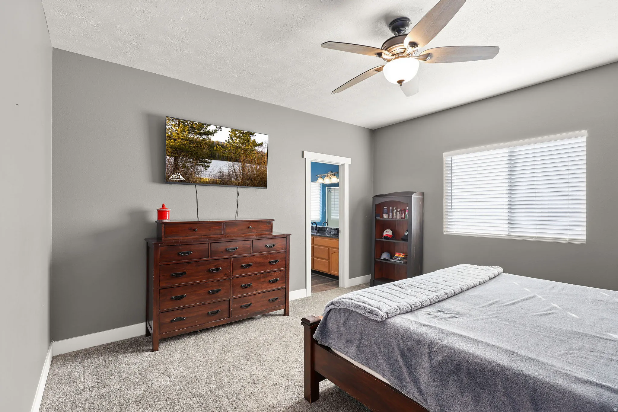 Bedroom featuring light colored carpet, ceiling fan, ensuite bathroom, and a textured ceiling