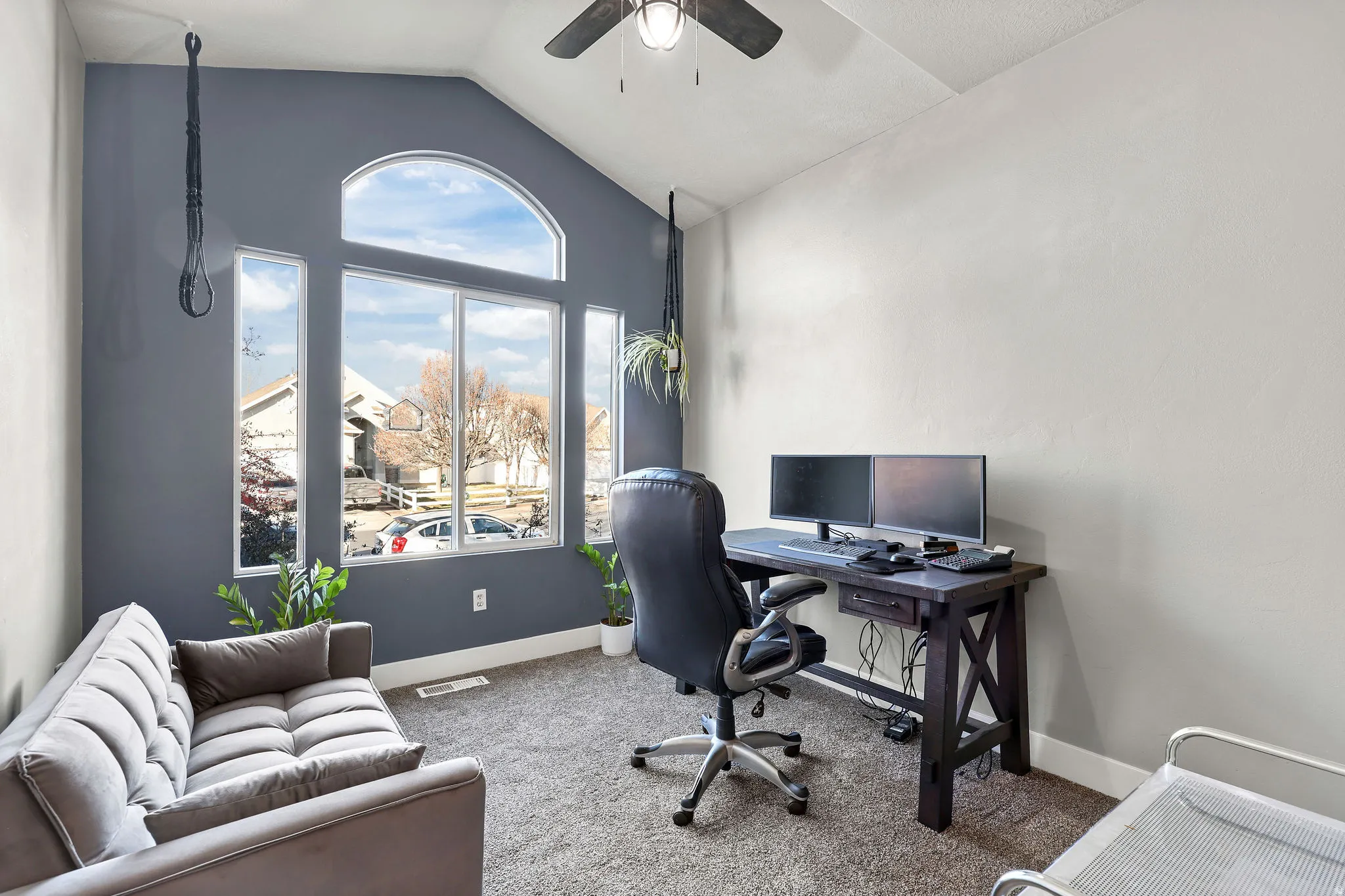 Carpeted office space with a ceiling fan and high vaulted ceiling