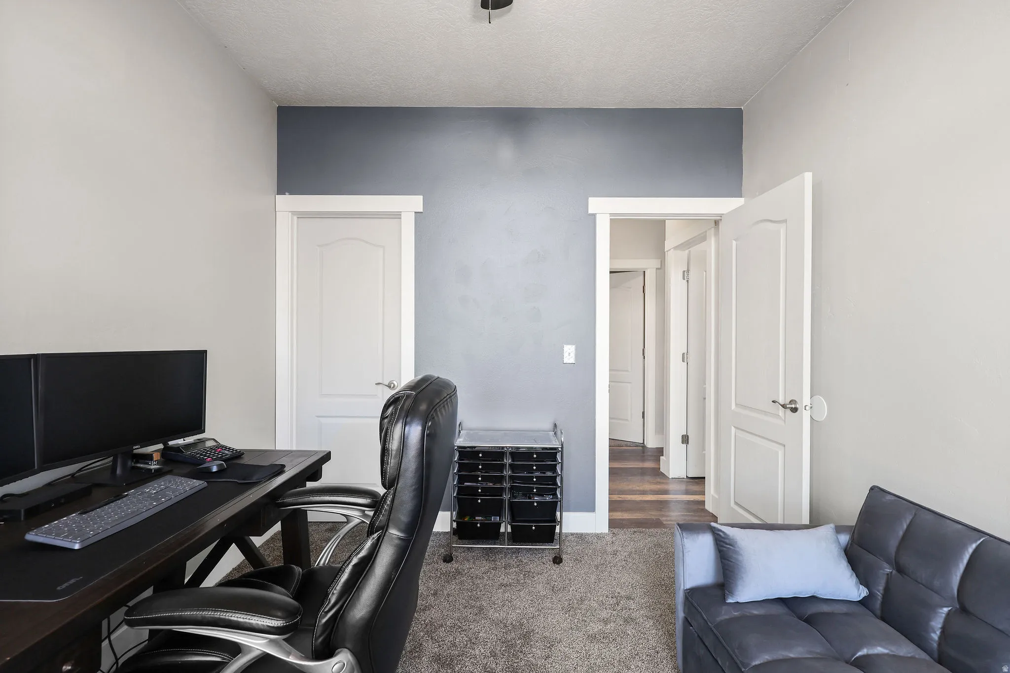 Office area featuring dark colored carpet and a textured ceiling