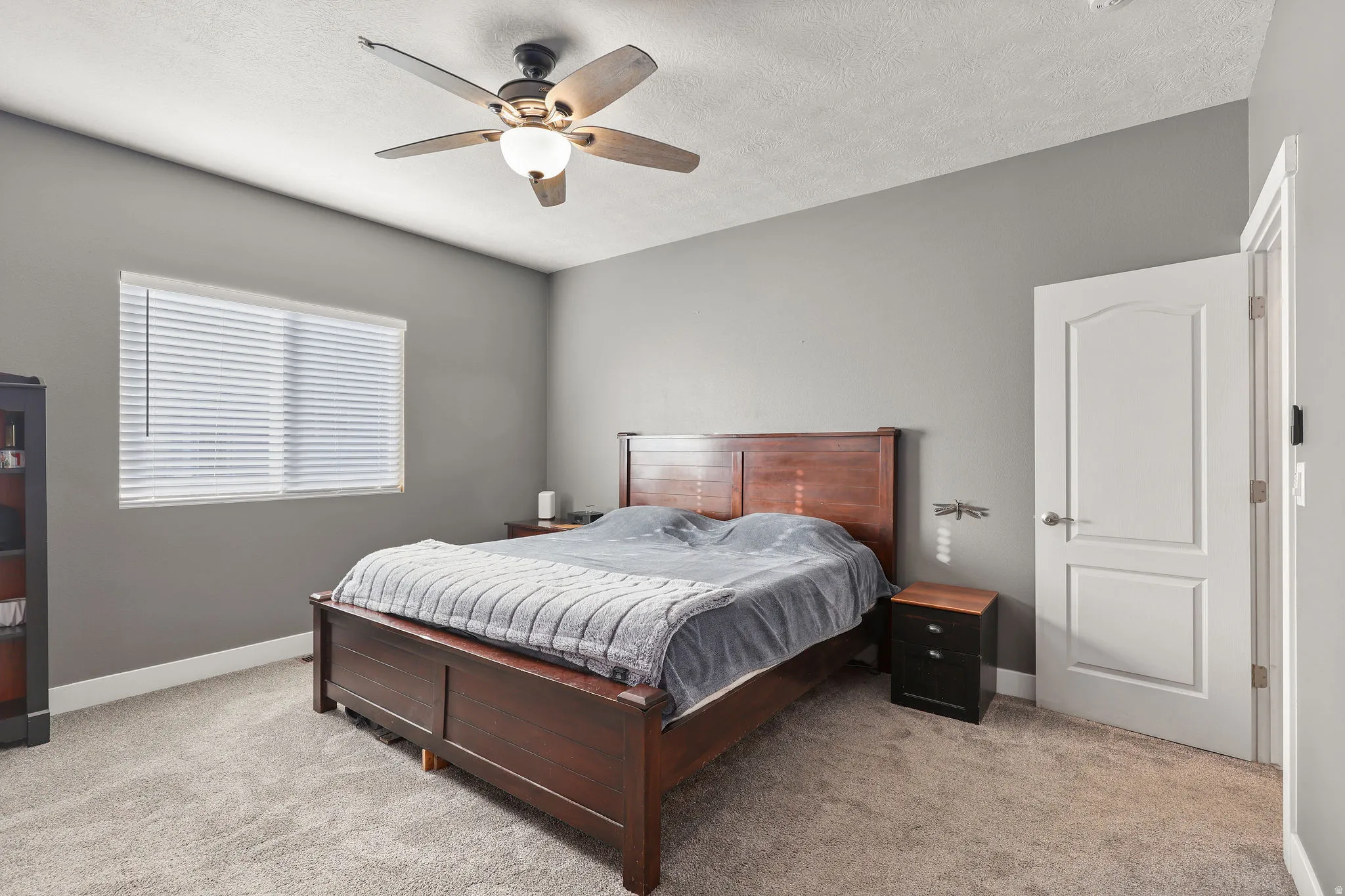 Bedroom with light colored carpet, ceiling fan, and a textured ceiling