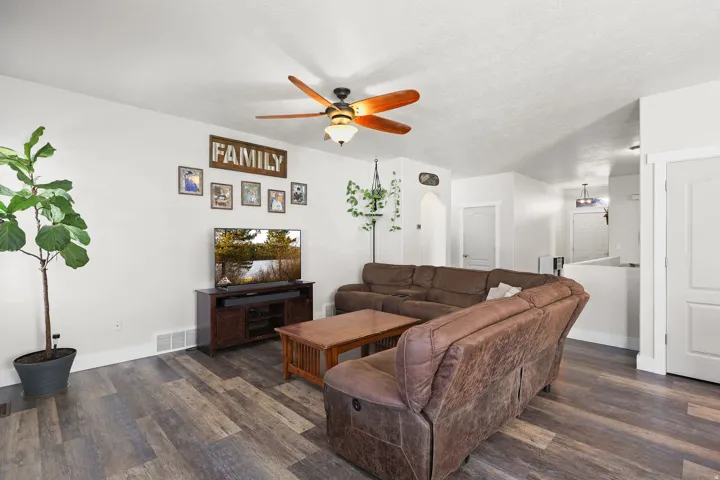 Living area featuring ceiling fan, dark wood-type flooring, a textured ceiling, and arched walkways