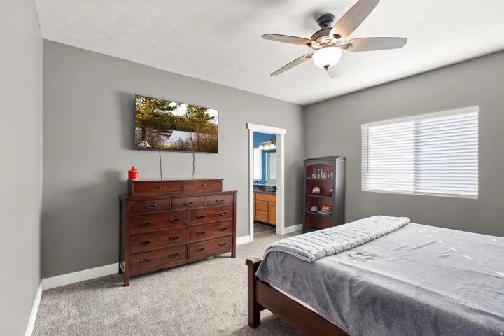 Bedroom featuring light colored carpet, ceiling fan, ensuite bathroom, and a textured ceiling