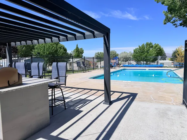 Swimming pool area featuring a perimeter fence and mature trees