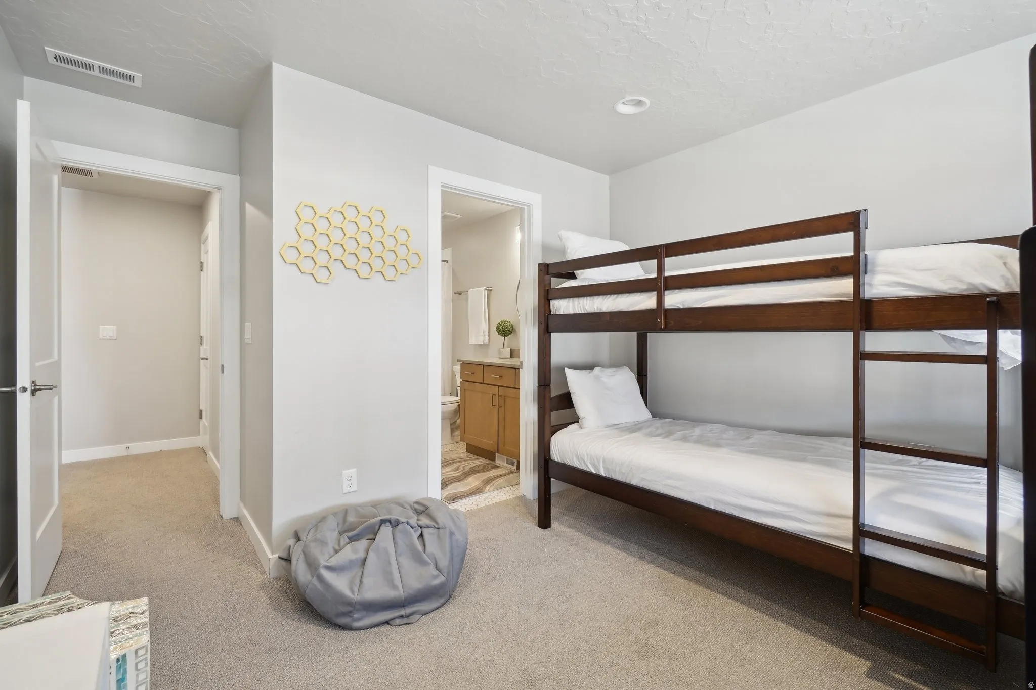 Bedroom with light carpet, connected bathroom, and a textured ceiling