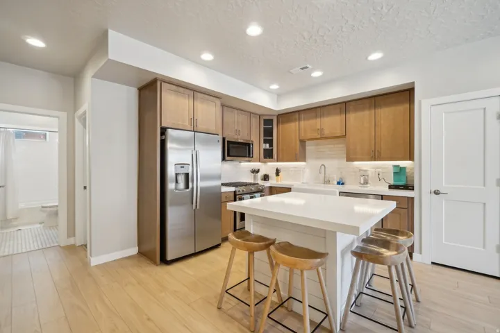 Kitchen featuring stainless steel appliances, a kitchen bar, brown cabinetry, a kitchen island, and glass insert cabinets