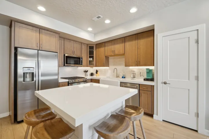 Kitchen featuring a kitchen bar, stainless steel appliances, brown cabinetry, light wood finished floors, and recessed lighting
