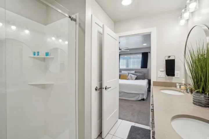 Ensuite bathroom featuring double vanity, light tile patterned floors, light carpet, a shower stall, and recessed lighting