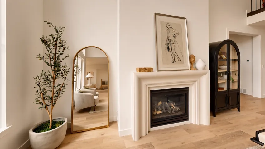 Hardwood-style flooring, a gas fireplace with a classic mantel, and an arched display cabinet