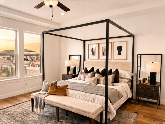 Tray ceiling with a ceiling fan, two large windows, wood-finish flooring, and a built-in headboard