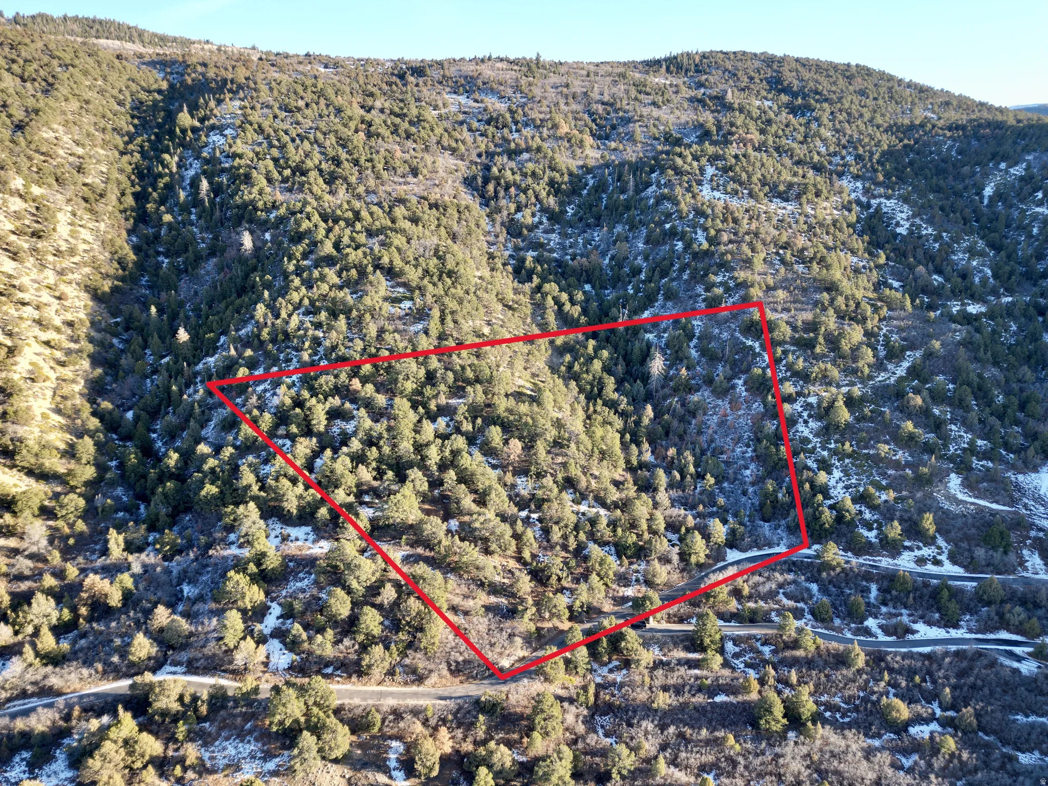 Aerial view of property and surrounding area featuring property boundaries highlighted and a mountainous background
