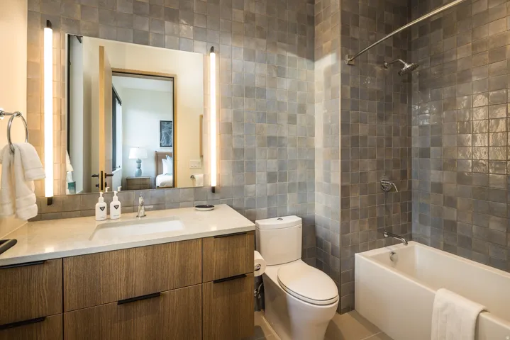 Full bath featuring tile walls, vanity, washtub / shower combination, and light tile patterned flooring