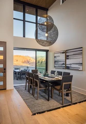 Dining room with light wood-style floors, a towering ceiling, and a water view
