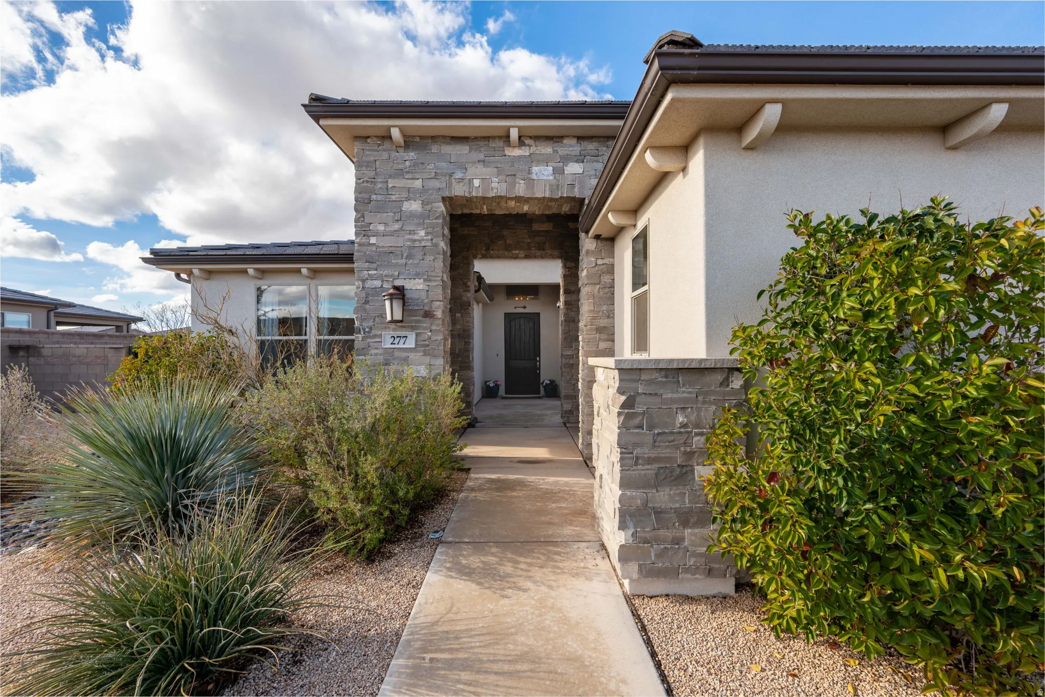 Doorway to property featuring stucco siding and stone siding
