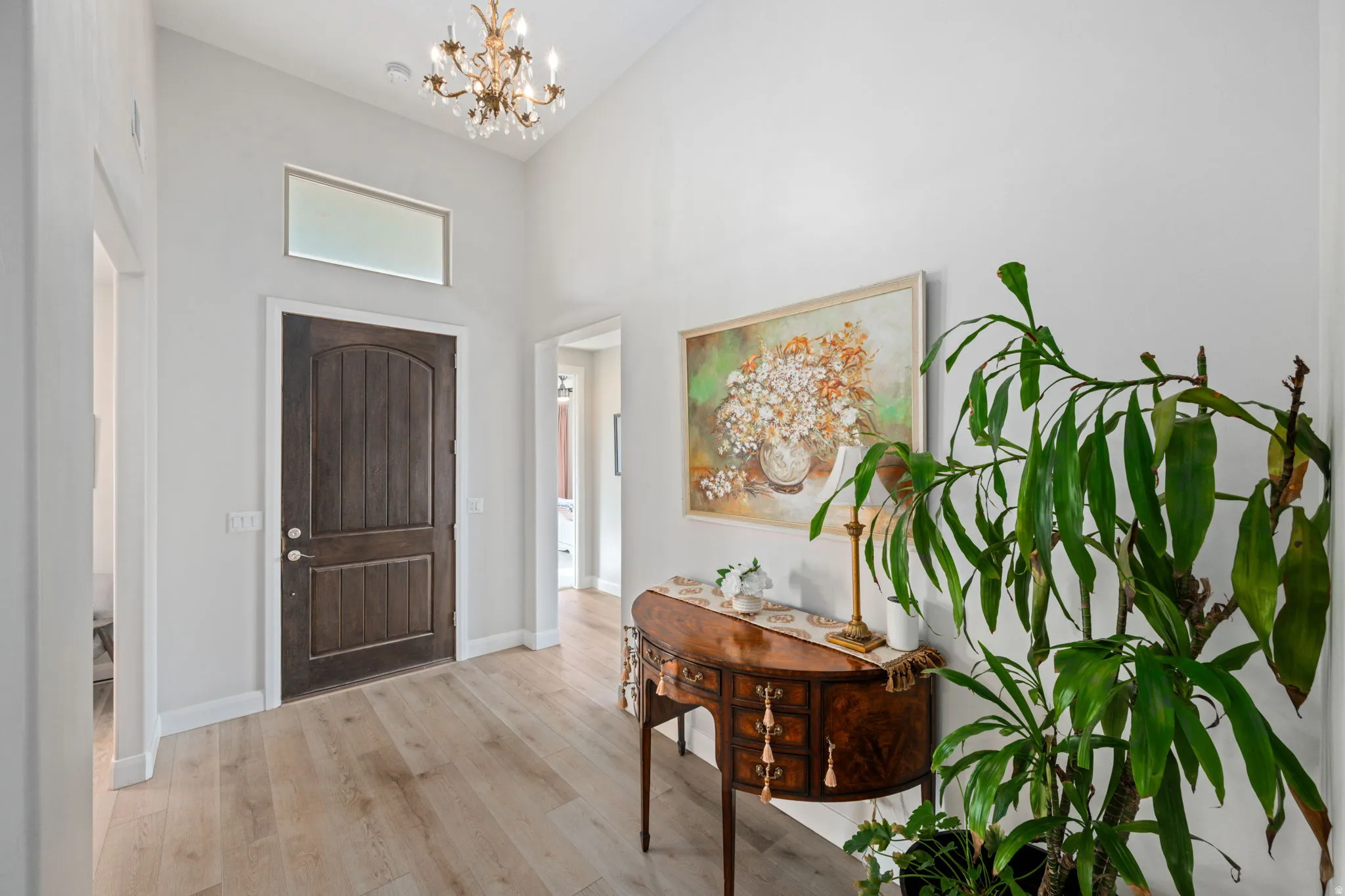 Entrance foyer with wood finished floors, a chandelier, and a towering ceiling